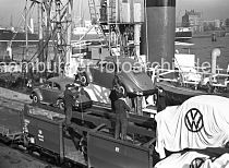 438_12 Die Arbeiter stehen auf der oberen Plattform des Gterwaggons und berwachen die Verladung eines Volkswagens - der fabrikneue Kfer schwebt im Ladegeschirr ber der Kaianlage am Oderhafen und wird gleich in den Laderaum 