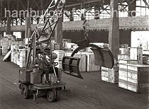 628_64 Arbeitserleichterung durch den Einsatz von Maschinen im Hafen Hamburgs: in einem Lagerschuppen fhrt der Fahrer einen Papierballengreifer durch den Gang zu seinem Arbeitseinsatz.