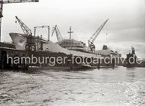 768_3 Die TINA ONASSIS luft 1953 auf der Werft HOWALDSWERKE HAMBURG AG vom Stapel - das 236,40m lange und 29,10m breite Turbinentankschiff hat eine Tragfhigkeit von 49 722 t. Nach dem Stapellauf liegt der Tanker, der zur Flotte des griechischen Reeders Onassis gehrt am Ausrstungskai der Schiffswerft. Im Vordergrund der Anleger fr Barkassen und Hafenfhren.