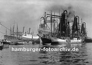 0954011 Im Waltershofer Hafen liegen Schiffe im Hafenbecken; ein Frachter wird mit einem schwimmenden Getreideheber gelscht - das Schttgut wird direkt in lngsseits liegenden Kstenschiffe geladen. 