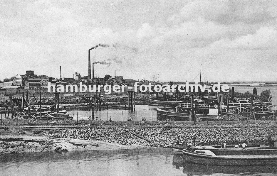 k_0954023 Schiffe im Harburger Liegehafen - im Vordergrund arbeiten Schiffer auf einer Schute - rechts ist die Sderelbe zu erkennen; im Hintergrund qualmende  Industrieschlote und Harburger Fabrikgebude.