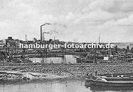 k_0954023 Schiffe im Harburger Liegehafen - im Vordergrund arbeiten Schiffer auf einer Schute - rechts ist die Sderelbe zu erkennen; im Hintergrund qualmende  Industrieschlote und Harburger Fabrikgebude.