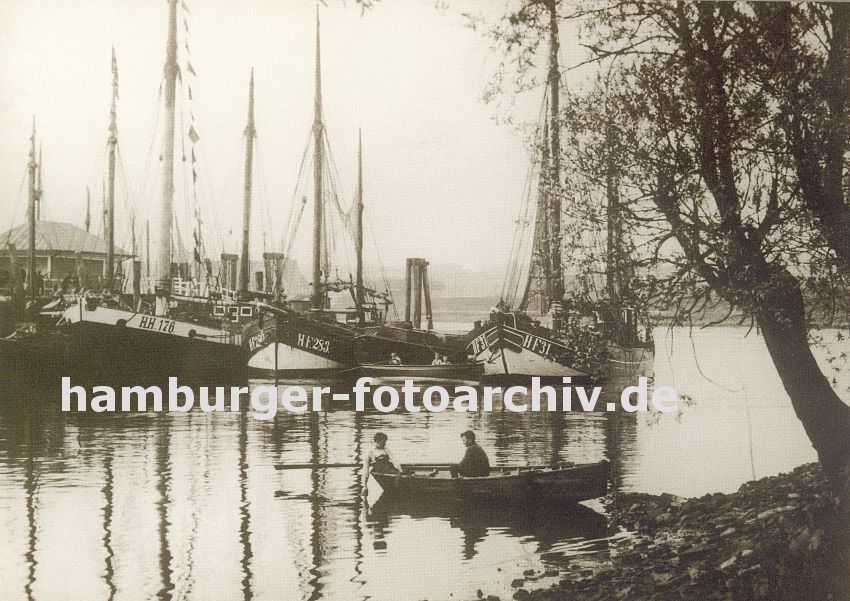 k_0954024 Fischkutter liegen an den Landungsbrcken von Hamburg Finkenwerder - ein Ruderboot mit zwei Jungen an Bord liegt am Ufer. Im Hintergrund ein weiteres Ruderboot mit Kindern.