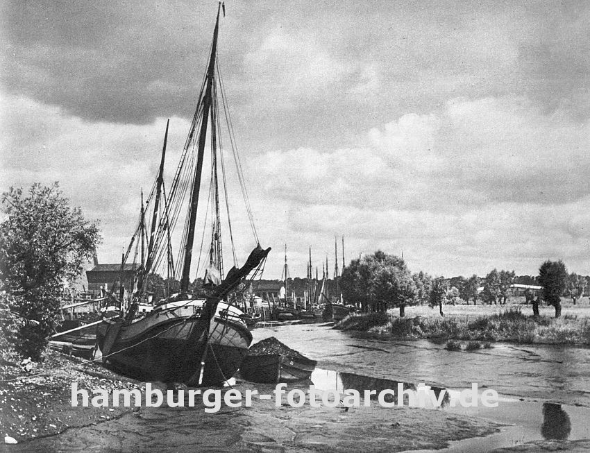 0954029 das Khlfleet in Hamburg Finkenwerder bei Ebbe - das Fleet ist fast trocken. Die Frachtschiffe, Fischkutter und Schuten liegen im Schlick; am gegen ber liegenden Ufer stehen Weiden an der Wiese.