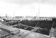 0954036 ein Tanker liegt im Hamburger Petroleumhafen am Kai - an Land sind Fsser gestapelt. Auf der gegenber liegenden Seite des Hafenbeckens sind runde Tanks zu erkennen.