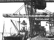 0954041 historisches Hamburg alte Fotografien von Hamburg Altona - Kohlekai am Altonaer Hafen; der Greifer der weit ausladenden Krananlage holt die Kohle aus dem Laderaum des Frachters  und ldt seine Fracht am Kai ab. Dort lieg die Kohle in Bergen  - ein Lastwagen mit grossem Anhnger wartet darauf mit Kohle beladen zu werden. 