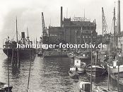 0954046 Blick auf den grossen Kohlespeicher am Hafen von Hamburg - Altona; grssere Schiffe und kleine Boote liegen am Kai oder den Dalben; im Vordergrund zwei Sport-Segelboote. Kaikrane strecken ihre Ausleger in den Himmel.