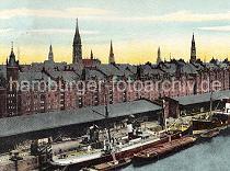0141_237_76_1  Zwei Dampfschiffe liegen am Sandtorkai des Sandtorhafens. Auf der Landseite werden die Schiffe über Kräne be- und entladen und auf der Wasserseite Schuten und Lastkähne liegen. Hinter den offenen Lagerschuppen, in denen gestapelte Güter zu erkennen sind, liegen die Gebäude der Speicherstadt - im Hintergrund Rathausturm und die Kirchtürme der Hansestadt Hamburg. Baubeginn der Speicherstadt war 1883. Dabei wurden zunächst die ab dem 16. Jahrhundert auf den Elbinseln Kehrwieder und Wandrahm gewachsenen Wohnviertel abgerissen. Der Kehrwieder galt als Arbeiter- und Handwerkerviertel mit teilweise enger Gängeviertelbebauung, der Wandrahm war vor allem mit Kaufmanns- und Bürgerhäusern aus dem 17. und 18. Jahrhundert bebaut und insbesondere von holländischen Einwanderern geprägt. Die Realisierung und Verwaltung der Speicherstadt wurde im Jahr 1885 durch die Hamburger Freihafen-Lagerhaus-Gesellschaft (HFLG) übernommen. Bis 1889 entstanden zwischen Kehrwiederspitze und Kannengießerort etwa 60 Prozent der Lagerflächen (Blöcke A bis O). Im zweiten Bauabschnitt von 1891 bis 1897 wurden die Speicherblöcke P, Q und R am St. Annenufer und Neuer Wandrahm errichtet. Im dritten Bauabschnitt von 1899 bis 1927, unterbrochen durch den Ersten Weltkrieg und die Inflationsjahre, wurde das Gebiet östlich der Straße Bei St. Annen fertig gestellt (Blöcke S bis X). Das "Rathaus" der Speicherstadt, das Verwaltungsgebäude der HHLA, wurde 1903 eingeweiht. Insgesamt entstanden 24 Speicherblöcke mit rund 300.000 Quadratmeter Lagerfläche.