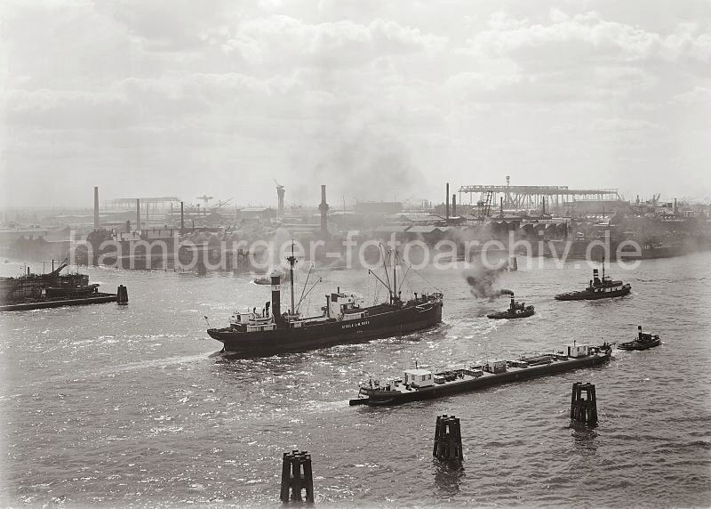 Werftanlagen der Deutschen Werft - Frachter mit Schlepper; ca. 1930 285_609a Blick über die Norderelbe zu den Werftanlagen der  Deutschen Werft; im Vordergrund Holzdalben, ein Frachter wird mit einem Schlepper aus dem Hamburger Hafen gezogen. 