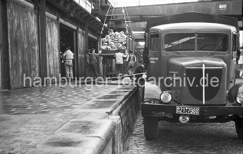 Hieve mit Bananenbschel, Hafenarbeiter - Lastwagen /  Segelschiffhafen 1949 447_5 Die Ladung des Bananenfrachters wird gelscht - eine Hieve wird von den Arbeitern auf die Laderampe dirigiert - ein Lastwagen mit dem Kennzeichen der britischen Besatzungszone steht vor dem Lagerschuppen - ein Brett fhrt als Auffahrt auf seine Ladeflche.