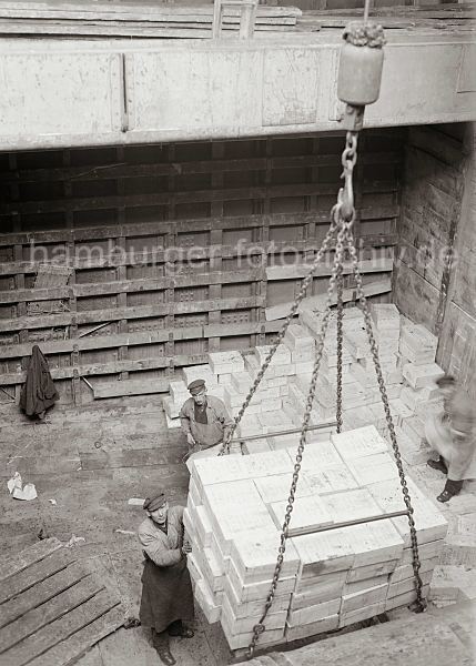 historische Bilder von der Arbeit im Hamburger Hafen; ca. 1932. Alte Hafenbilder aus dem Fotoarchiv der Hamburger Hafen und Logistik AG. 469_576 Die Ladung Rosinenkisten ist von den Stauern auf dem Ladegeschirr des Krans verstaut und wird aus dem Laderaum des Frachters gehievt.�