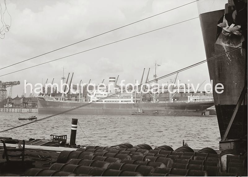 alte Bilder aus Hamburgs Hafen / Hamburger Fotoarchiv der Hamburger Hafen und Logistik AG // Frachter im Kaiser Wilhelm Hafen - Auguste Victoria Kai / Kronpinzen Kai; ca. 1936. 533_745 Der Frachter Burgenland liegt am Auguste Victoria Kai des Hamburger Kaiser Wilhelm Hafens. lm Vordergrund der Bug mit dem Anker eines Schiffs am Kronprinzen Kai. Fsser liegen auf der Kaianlage zum Abtransport bereit.