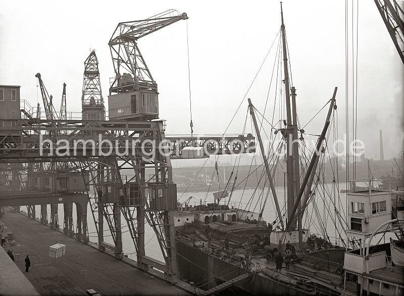 Alte Hamburgbilder aus dem Hafen / Gterumschlag im Hamburger Oderhafen - Dreifachkran am Chilekai; Frachtschiff im Hafen Hamburgs; ca. 1934. 542_182 Ein Frachter liegt am Chilekai im Oderhafen, eines der vielen Hafenbecken Hamburgs. ber einen Dreifachkran werden grosse Frachtkisten an Bord des Schiffes gebracht. Im Hintergrund die Kaischuppen am Mnckebergkai des Ellerholzhafens.