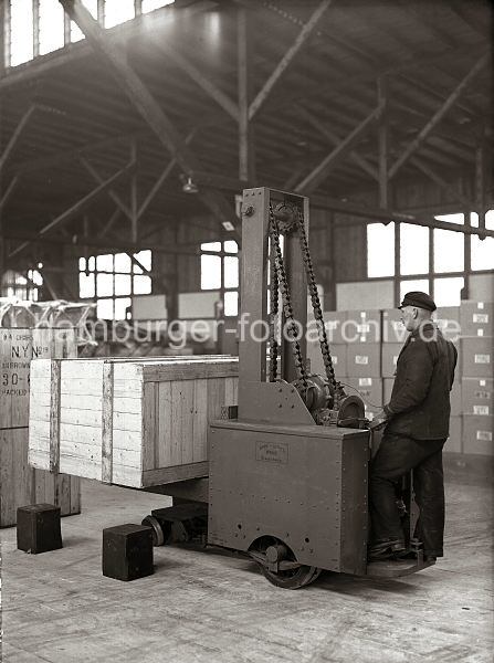 Hamburger Bilder als Poster - Fotos als Geschenk zum Jubilaeum, Geburtstag oder Weihnachten. Hubkarre Amme Luther - Transportkiste; ca. 1934.  545_185 Mit einer Hubkarre der Herstellerfirma Amme Luther hebt ein Lagerarbeiter eine groe Holzkiste an. Im Hintergrund sind weitere Kisten in dem Lagerschuppen des Hamburger Hafens gestapelt. 