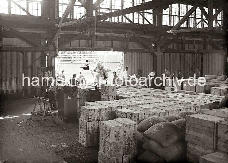 Altes Bildmaterial vom berseehafen Hamburg. Gterumschlag am Dalmannkai, Grasbrookhafen - Lagerung im Kaischuppen, Hafenarbeiter mit Sackkarren; ca. 1936. 608_674 Die Ladung eines Frachters wird am Dalmannkai des Hamburger Grasbrookhafens gelscht - eine Hieve Scke wird gerade auf der Laderampe abgesetzt. Ein Lagerarbeiter zieht eine Sackkarre schwer mit Scken beladen in den Kaischuppen, andere warten mit der leeren Handkarre auf die Ladung.