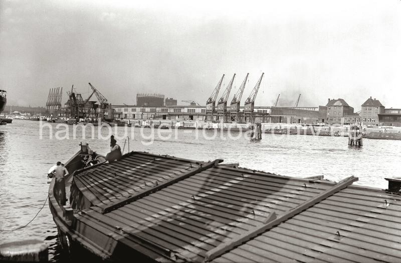 ilddokumente vom historischen Hafen Hamburgs -  Bilder aus dem Fotoarchiv der HHLA. Schute im Sdwest Hafen - Getreideheber und Krne am neuerrichteten Togokai; ca. 1934.  622_16_B_208 Im Vordergrund eine abgedeckte Schute am Afrikakai des Hamburger Sdwesthafens - einige Schiffer befinden sich am Bug des groen Lastkahns. Auf der gegenber liegenden Seite des Hafenbeckens die neu errichtete Kaimauer des Togokais und dem Verteilungsschuppen 58. Ein schwimmender Getreideheber und Schuten liegen am Kai - im Hintergrund ist das Gasometer der Gaswerke auf dem Grasbrook zu erkennen.