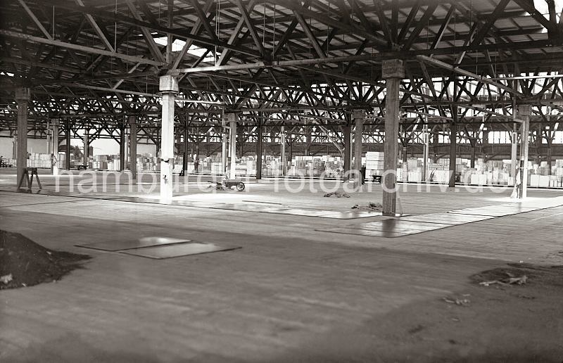 Historische Hamburg-Bilder aus dem Archiv der HHLA: Fertigstellung Neubau Verteilungsschuppen 58. 622_25_B_207 Blick durch den neu errichteten Verteilungsschuppen 58, der als Erweiterungsbau des Schuppen 57 konstruiert worden ist. In der Bildmitte liegt noch eine Holzschubkarre mit Schaufeln im Bauschutt - im Hintergrund stapelt sich das Lagergut im Schuppen 57 am Kamerunkai.
