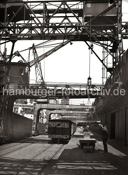 Ladung Kupferbarren l�schen - Hamburger Hafen; ca. 1932. Alte Fotografien von der Arbeit im Hamburger Hafen aus dem - Bildarchiv der HHLA.  633_55 Eine Ladung Kupperbarren wird von dem am Hafenkai liegenden Frachter gel�scht. Mit dem Kran werden die Metallbarren von Bord geholt und auf einem Elektroschlepper abgelegt. Ein Hafenarbeiter steht auf dem F�hrerstand des Elektrokarrens, ein anderer f�hrt die am Kranhaken h�ngenden Barren zur Ladefl�che.