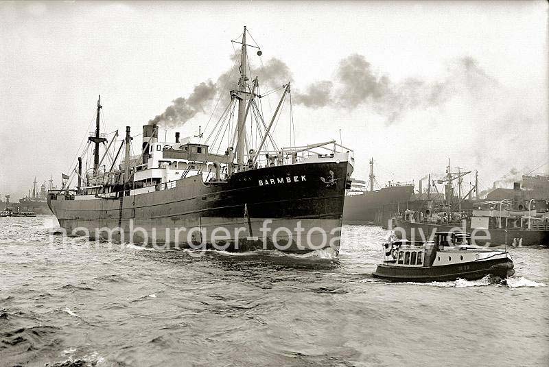 Alte Bilder von Schiffen aus dem Hamburger Hafen - Stckgutfrachter BARMBEK, Barkasse auf der Elbe; ca.1938.  748_B_280b Der Frachter BARMBEK der Reederei Knhr & Burchard verlsst den Hamburger Hafen - er fhrt ohne Schlepperhilfe auf der Elbe flussabwrts, eine Barkasse fhrt vor dem Bug des Schiffs. Im Hintergrund hat das Frachtschiff LEONIAN in der Reiherwerft eingedockt.