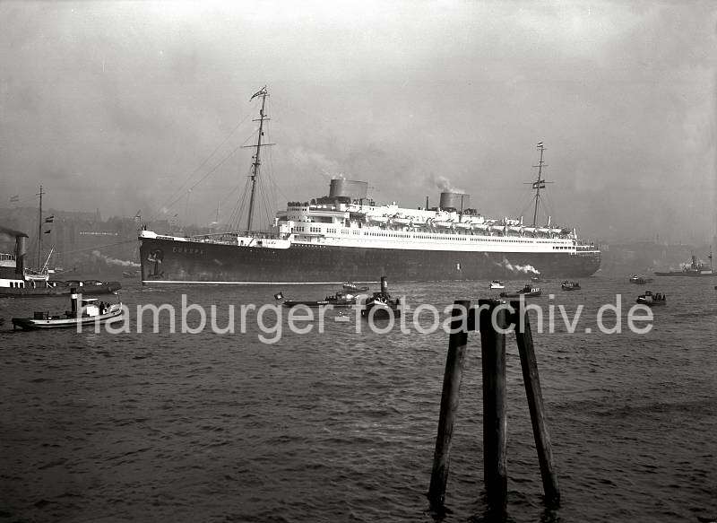 Historische Schiffsfotos - Luxus-Passagierschiff EUROPA - Nordatlantik-Liner der Norddeutschen Lloyds. Alte Hamburg Bilder als Geburtstagsgeschenk, auf Fotoleinwand oder Fotopapier.  778_197a Das Luxus-Passagierschiff EUROPA beim Auslaufen aus dem Hamburger Hafen -  im Hintergrund Speicher und Industriegebude von Altona. Der 282,77m lange und 30,65m breite Turbinendampfer wird von Schleppern in die Fahrrinne der Elbe gezogen.