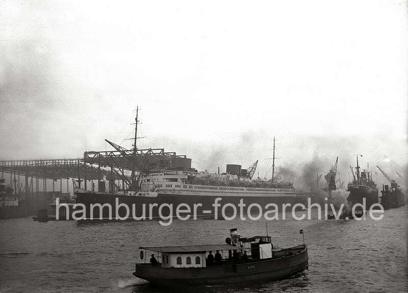 Alte Schiffsfotos - Passagierschiff EUROPA - Werft Blohm & Voss; 1930. Alte Hamburg Fotos zum Firmenjubilaeum / Fotoleinwand oder Fotopapier. 781_199a Der Passagierdampfer EUROPA liegt vor der Werft Blohm & Voss und wird fr das Auslaufen aus dem Hamburger Hafen vorbereitet. Im Hintergrund die Werftanlagen der Hamburger Traditionswerft; rechts liegt ein Motorschiff im Schwimmdock.