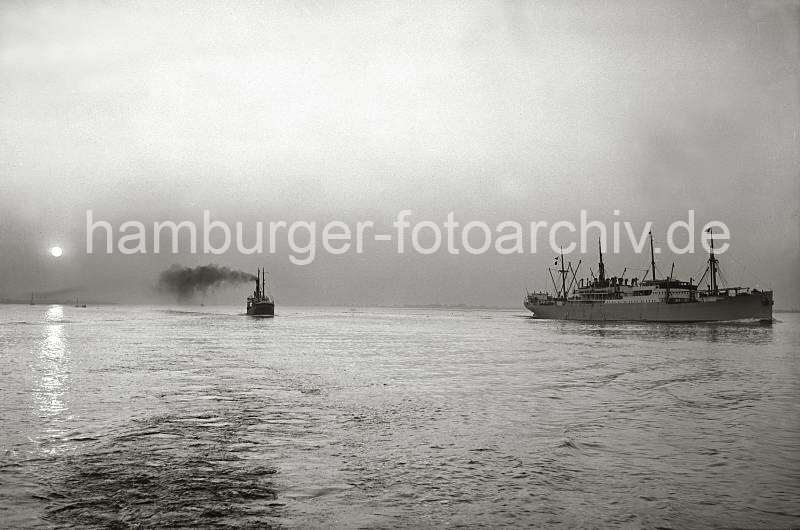 Historische Hamburgmotive Sonnenuntergang auf der Elbe - Schiffsverkehr, qualmender Schiffsschornstein -  Alte Hamburgaufnahmen als Prsent zur Hochzeit auf Fotoleinwand oder Fotopapier. 786_B_235 Zwei Frachtschiffe fahren in der Abenddmmerung auf der Elbe Richtung Hamburger Hafen - die Abendsonne spiegelt sich im Wasser des Flusses, dicker Qualm steigt aus einem Schiffsschornstein.