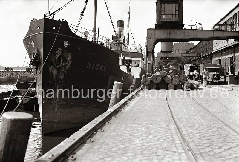 historische Fotos Altona - Ladung Baumstmme Tropenholz - Mercedes Lastkraftwagen mit Plane; ca. 1937. AltonaBilder als Kunstdruck auf Leinwand + Poster. 806_B_288a Die Ladung Tropenholz ist von dem Frachter NIOBE gelscht im Altonaer Hafen gelscht worden; Baumstmme liegen auf dem Kai gestapelt.  An der Laderampe des Schuppens steht ein Mercedes Diesel Lastkraftwagen Lo 2000, ein Kaiarbeiter bringt mit einer Stechkarre Transportgut heran.