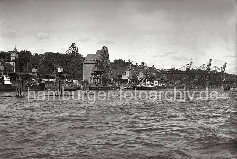 Alte Fotografien Altona - Getreidesilo, Getreideladung lschen - Getreideheber; ca. 1937. Altonafotos als Kunstdruck auf Leinwand + Poster; Hamburggeschenke. 809_B_222 Blick ber die Elbe in den Altonaer Hafen. An dem Getreidespeicher steht in groen Lettern die Aufschrift "GETREIDE PFLEGE; H. PAULSEN". Die Getreideladung eines am Kai liegenden Dampfers wird ber die Sauganlage der beiden Getreideheber gelscht. Auf der Kaianlage liegen Fsser - auf den Gleisen der Hafenbahn stehen Khlwagen mit der Aufschrift "SEEFISCHE". Im Hintergrund der Kai des Altonaer Kohlehafens.