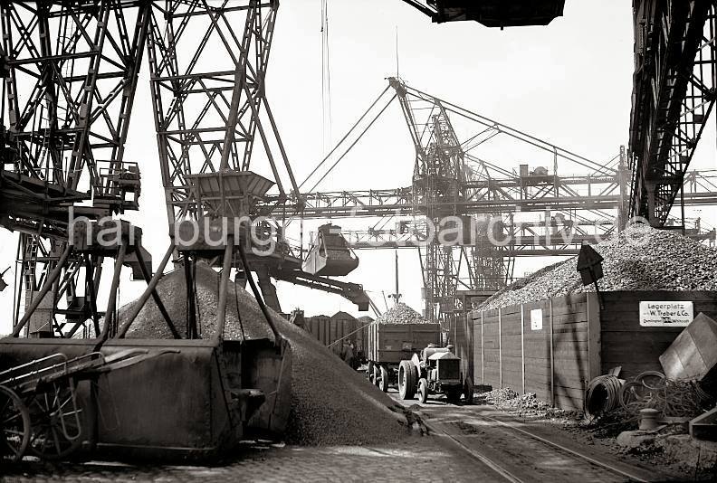 Historische Bilder Hamburg Altona - Kohlenlager im Altonaer Kohlehafen - Zugmaschine mit Anhnger, Krananlage; 1938. Altonaer Bilder auf FotoleinwandLeinwand + als Fotoposter. 816_B_221a Auf dem Kai des Altonaer Kohlenlagers wird die angelandete Kohle gelagert. Die Greifer holen die Ladung von dem Frachtschiff und fllen die Kohle in einen Trichter, von dem ber Frderbnder das Schttgut verteilt wird. Eine Zugmaschine steht mit einem hoch beladenen Anhnger auf dem Kaigelnde; im Vordergrund eine einachsige Holzkarre, mit der kleinere Kohleladungen von Hand transportiert werden.