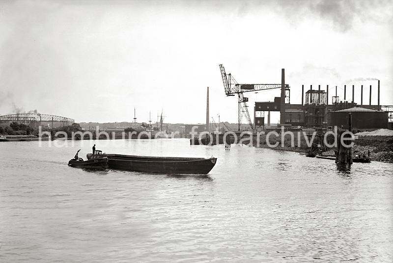 Alte Harburger Bilder - Schute mit Barkasse vor dem Harburger Seehafen 3; ca. 1938 - historische Harbugfotos als Geschenk zum Geburtstag, Jubilaeum + Weihnachten.  821_B_259 Blick von der Eine Schute wird von der Barkasse HERTA aus dem Harburger Seehafen 3 auf die Sderelbe geschleppt; der Ewerfhrter steht auf dem Heck seines Lastkahns. Ein Seeschiff und ein Frachtsegler liegen an den Dalben des Hafenbeckens; hinter den Masten des Segelschiffs ist der Turm der Heimfelder Kirche St. Paulus zu erkennen.