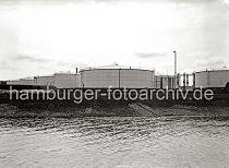 823_B_259a IBlick über das geböschte Ufer der Süderelbe auf die Öltanks des Öllagers im Harburger Hafen.