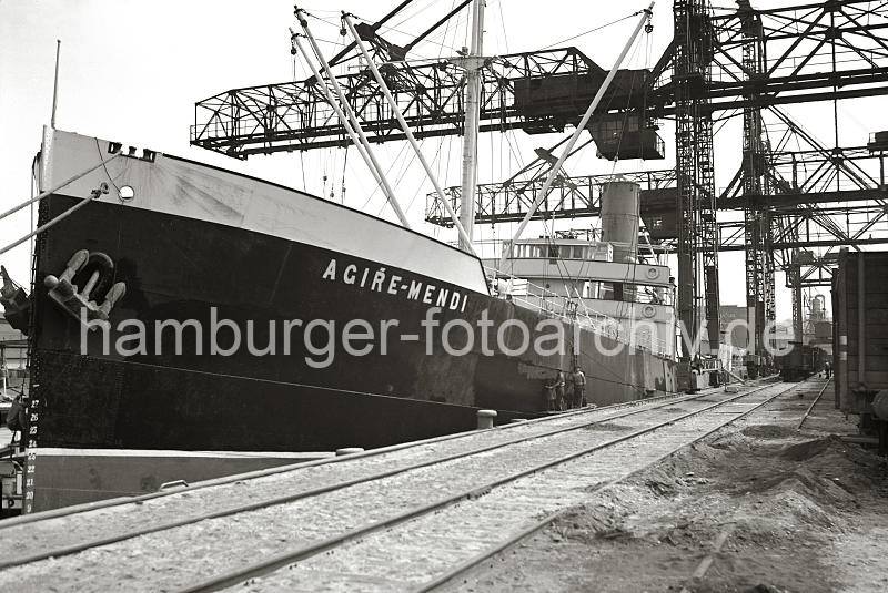 Alte Harburger Hafenaufnahmen - Kohlenschiff am Kai des Harburger Hafens, Gterwagen + Kohlekran; ca. 1938 - Alte Harburg Bilder als Geschenk zum Geburtstag, Jubilaeum + Weihnachten. 827_B_261 Die Kohlefracht des Seeschiffs AGIRE-MENDI wird im Seehafens Harburg gelscht. Auf dem Kai die auf Rdern laufenden Krananlagen, die die Kohle an Land transportieren und gleich in die Gterwaggon verladen.