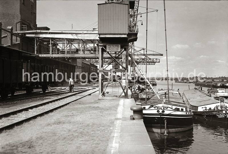 Alte Harburger Fotografie - Binnenschiffe / Elbkhne im Harburger Seehafen - Ladung Schttgut per Sauganlage lschen - Alte Harburg Bilder als Geschenk zum Geburtstag, Jubilaeum + Weihnachten.  829_B_263 Mehrere groe Elbkhne und motorisierte Binnenschiffe liegen an der Kaimauer eines der drei Harburger Seehafenbecken. ber eine Sauganlage wird die Ladung der Schiffe gelscht und per Frderband in das Silo transportiert. Im Hintergrund die Sderelbe und Wilhelmsburger Industrieanlagen.