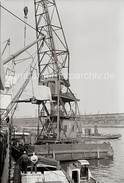 Historische Hamburg-Fotografie - Schwimmkran Autobus Verladung - Alte Hamburg Motive als Geschenk zum Jubilaeum, Geburtstag + Weihnachten. 837_B_303a Der Schwimmkran den BSSING NAG Autobus vom Gterwagenabgeladen und zum Frachter transportiert in dessen Laderaum der Bus verladen werden soll. Im Hintergrund die Schuppen O'swaldkai.