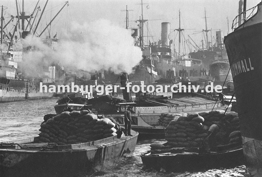 0953977 historisches Hamburg - Dokumente der Hamburger Geschichte - geschftiges Treiben im Hamburger Hafen ca. 1930; Frachter liegen an den Duckdalben in der Mitte des Segelschiffhafens. Ein Schlepper zieht unter Dampf eine Schute im Hafenbecken.