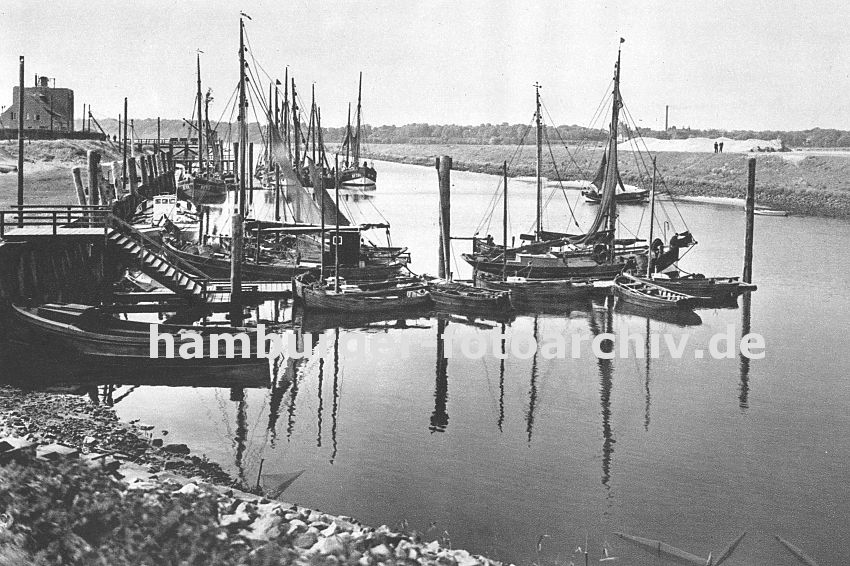 0954026 Hafenanlage von Hamburg Finkenwerder; Fischkutter liegen am Stecg oder an Dalben; dazwischen kleinere Holzboote - links im Vordergrund ein offenes Festmacherboot. Vom Kai fhrt eine Wassertreppe zum Bootssteg hinunter.