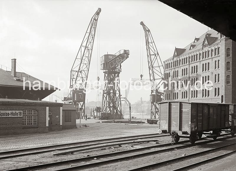 Historische Hafenanichten aus dem Fotoarchiv der HHLA -  Schwimmkrane am Kaiserhft, Rckseite Kaischuppen 13 + Speisehalle. 1162_532 Ein Gterwaggon mit einem schweren Maschinenteil ist ber die Drehscheibe auf das Gleis an den Kai des Kaiserhft gebracht worden. Einer der Schwimmkran hat die Last schon am Haken. Im Hintergrund sind die Werftanlagen der Deutschen Werft am Reiherstieg zu erkennen. Links die Speisehalle 16 des 1887 gegrndeten Verein fr Volkskaffeehallen, dort gab es fr die Hafen- und Werftarbeiter preiswerte warme Speisen und Kaffee, weswegen die Einrichtungen auch Kaffeeklappen genannt wurden.  Hinter der Speisehalle das Dach des Kaischuppen 14 am Dalmannkai des Grasbrookhafen und lks. die Fassade des Kaiserspeiches.