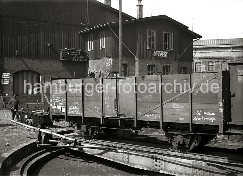 Historische Fotografien vom Hamburger Hafen - Eisenbahn-Drehscheibe - Gterwaggon, Einachsschlepper; ca. 1934.  01162_532 Der Arbeiter zieht mit Hilfe eines Einachsschleppers einen Gterwaggon einer Drehscheibe am Strandkai bei den Gaswerken. Die Drehscheibe wird eingesetzt um Gterwagen auf geringer Flche ohne Einsatzmglichkeiten von einer Weiche auf das bentigte Gleis zu bringen. Der Waggon trgt den Aufdruck "Gorny Slask, Oberschlesien"; an der Hausfassade weist ein Emailleschild darauf hin, dass eine Einfahrt nur zwischen Schuppen 20 und 21 mglich ist. Ebenfalls befindet sich an der Hausfront ein Taubenschlag mit Tauben und ein Vogelhaus.