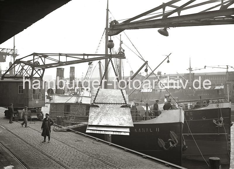 Grasbrookhafen alte Hamburg Bilder auf Fotoleinwand oder Posterpring - Verladung von Blechplatten im Sandtorhafen / Sandtorkai, Hafenkran; ca.1934. 01176_62 Blechplatten in dem Anschlag des Kranhakens ber dem Kopfsteinpflaster des Sandtorkais. Zwei kleinere Motorschiffe liegen neben einander am Kai, eine Gangway fhrt an Land. Im Hintergrund die Kaischuppen 12 + 13 am Kaiserkai.