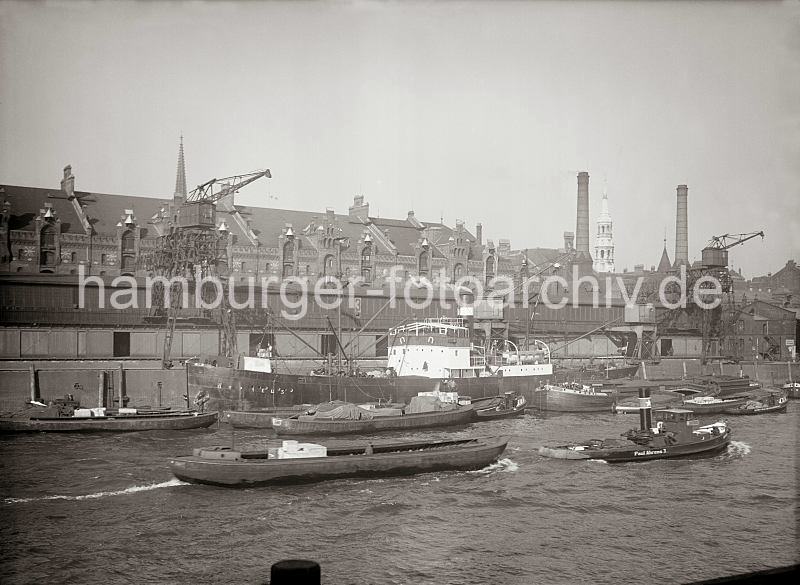 Historische Fotodokumente aus dem Archiv der HHLA Schlepper mit Schute im Sandtorhafen / Frachtschiff am Sandtorkai, Schuppen 3; alte Hamburg Bilder auf Fotoleinwand oder Posterprint. 011778_432 Der Frachter ORPHEUS liegt vor dem Schuppen 3 des Sandtorkais - Schuten und Lastk�hne haben l�ngsseits fest gemacht.  Ein Schlepper zieht eine Schute durch das Hafenbecken; im Hintergrund die Giebel der Speicherstadt und die Kircht�rme der St. Nikolaikirche und St. Katharinenkirche. Rechts die Schornsteine des Kesselhauses am Sandtor.