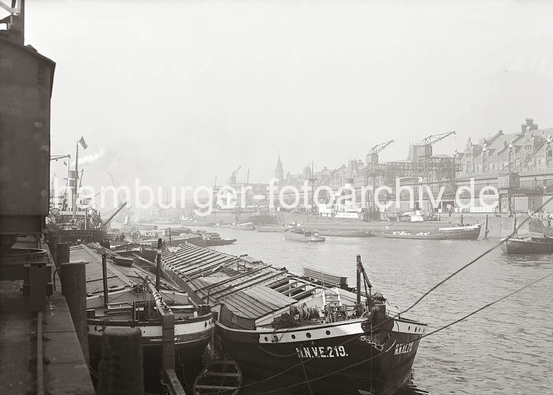 Alte Fotografien aus dem Bildarchiv der HHLA. Elbkhne am Kaiserkai / Sandtorhafen - Krananlagen am Sandtorkai - Dcher der Speicherstadt - Hamburgensien auf Leinwand oder Posterprints. 02183_721 Zwei breite Frachtkhne liegen an der Kaimauer des Kaiserkais - die Elbkhne haben keinen eigenen Antrieb sie wurden im Schleppverband die Elbe hinauf gezogen. Die Buchstaben N.N.V.E. am Bug eines der Khne sind die Abkrzung fr "Neue Norddeutsche und Vereinigte Elbeschiffahrt AG", eine Interessensgemeinschaft die 1929 aus dem Zusammenschluss der "Vereinigte Elbeschiffahrts-Gesellschaft, AG" und der "Neue Norddeutsche Fludampfschiffahrt-Gesellschaft, Hamburg" entstand. Diese Aktiengesellschaft hatte ihren Sitz in Hamburg.