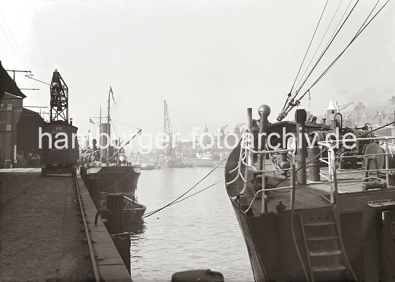 Alte Fotografien aus dem Bildarchiv der HHLA. Kaiserkai / Sandtorhafen - Rollkran auf den Schienen - Frachtschiffe am Hafenkai; ca.1934 - Hamburgenbilder auf Foto-Leinwand oder Posterprints.  02184_720a Der Kranfhrer bewegt den Hafenkran auf Schienen an der Kaimauer zu seinem Arbeitsplatz. Entlang des Kaischuppen-Dachs verluft eine Oberleitung - mit einem Stromabnehmer wird der Arbeitskran mit Strom versorgt. Hinter dem Bug des Frachters am Kaiserkai ist die andere Seite des Sandtorhafens zu erkennen; am gegenber liegenden Sandtorkai liegt ein Schwimmkran.