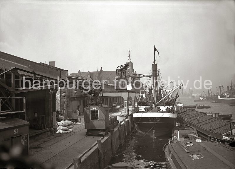 Laufkrane und Halbportalkrane am Kaiserkai / Sandtorhafen - Dampfer und Elbkhne; ca.1934 02186_86 Der Dampfer ALSTER hat am Kaiserkai fest gemacht, an seiner Seite liegen Schuten und Elbkhne. Am Halbportalkran hngt eine Hieve Kisten, die an Land gebracht und auf der Laderampe abgesetzt werden soll; im Hintergrund stehen dort Zugpferde und ein Wagen, der mit Kisten beladen ist.  Zwischen den Auslegern der Krananlagen ist der Uhrenturm des Kaispeichers A zu erkennen.