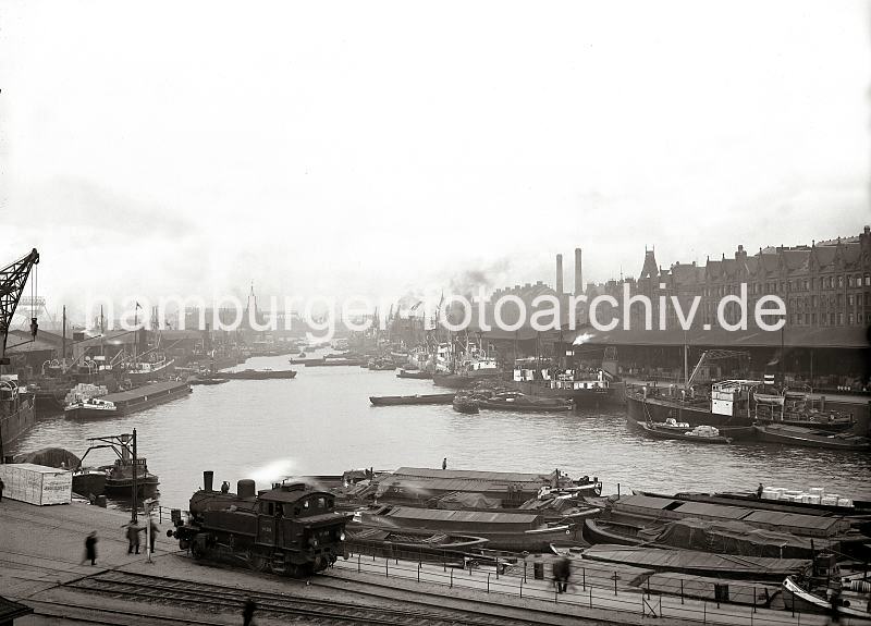 Historische Fotos aus dem Bildarchiv der Hamburger Hafen und Logistik AG HHLA - >Panorama vom Hamburger Sandtorhafen; ca.1934. Hamburgbilder auf Foto-Leinwand oder Posterprints. 02195_0077 Die Schiffe liegen dicht an dicht an den Kaianlagen des Sandtorhafens. Im Vordergrund steht eine Lokomotive unter Dampf auf den Gleisen der Hafenbahn. Am Kai liegen Schuten, deren Ladungen sind teilweise mit Persenning gegen die Witterungseinflsse abgedeckt. Zwischen den Giebeln der Speicherstadt ragen die Schornsteine  des Kesselhauses heraus.