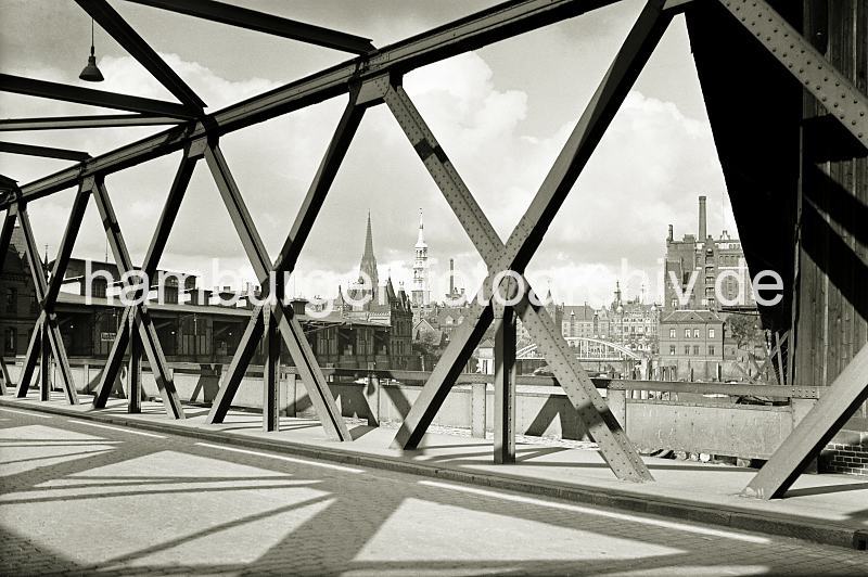Eisenkonstruktion der Baakenbrcke - Magdeburger Hafen, Fruchtschuppen C - historische Hafenfotografien aus dem Archiv HHLA. alte Hamburgbilder aus dem Hafen - Prints auf Leinwand / Posterprint als Geschenk fuer buero. 02201_OF_77A Blick durch die Eisentrger der Baakenbrcke, die den Magdeburger Hafen berspannt. Im Hintergrund die Bogenkonstruktion der Magdeburger Brcke, rechts davon der Kaispeicher B. Links die Kirchtrme der St. Nikolaikirche und St. Katharinenkirche und das Dach des Kaischuppens C im Magdeburger Hafen.