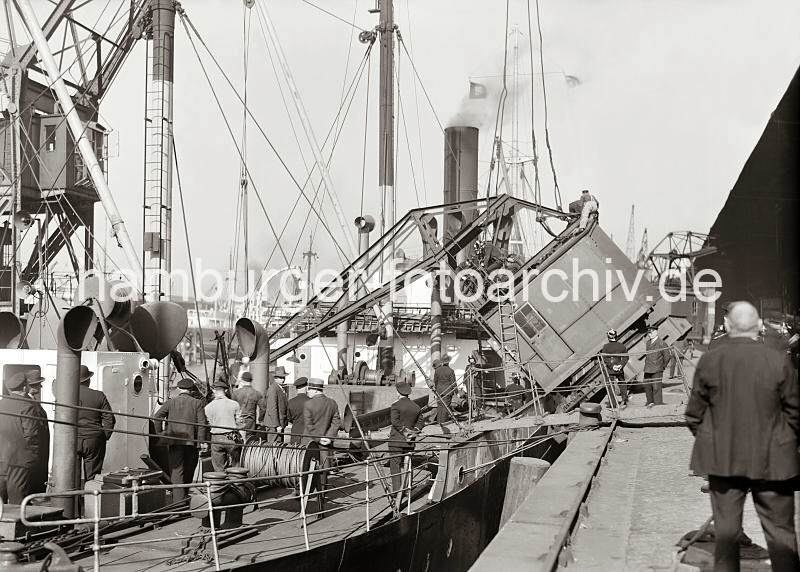 Historische  Fotografien von der Arbeit im Hamburger Hafen aus dem Archiv der HHLA. Umgestrzter  Rollkran im Baakenhafen - Schaulustige an Deck eines Frachters;ca. 1932.  02232_749 Ein Rollkran hat beim Lschen eines Frachtschiffs bergewicht bekommen und ist auf das Deck des Frachters gekippt. Feuerwehrleute und Kaiarbeiter legen eine Stahl-Trosse um den Kran, damit der auf der Wasserseite des Schiffs liegende Schwimmkran den verunglckten Kran anheben kann.