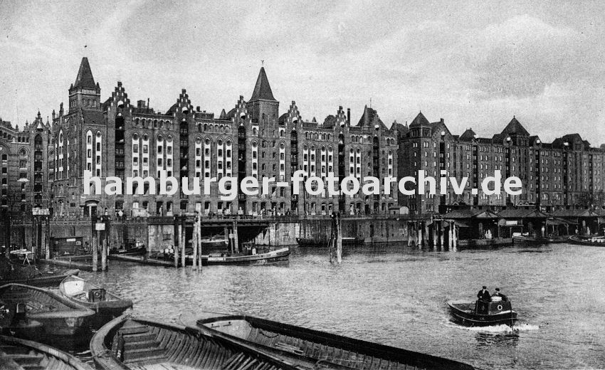 01147734 altes Hamburg Fotos - Blick über den Brooktorhafen zu den Speicherblöcken V + X. Schuten und Kähne liegen an der Kaimauer oder den Holz Duckdalben. Eine kleine Barkasse fährt durch das Hamburger Hafenbecken Richtung Magdeburger Hafen. 