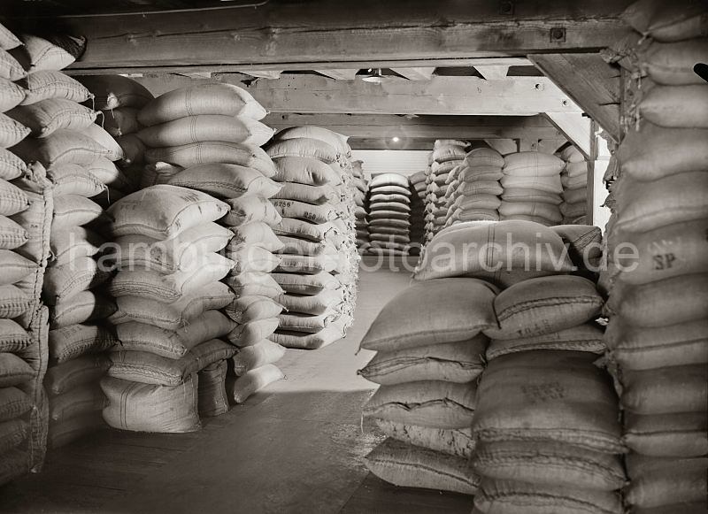 503_507a Bis unter die Decke des Lagerbodens sind Kaffeescke in einem Lagergebude der Speicherstadt gestapelt. 1885 wurde mit der Planung zum Bau der Hamburger Speicherstadt begonnen. Es entstand unter der Leitung des zustndigen Oberingenieurs Franz Andrea Meyer in neogotischer Architektur auf einer Gesamtflche von 630 000 der grte zusammenhngende Lagerkomplexes der Welt. Betrieben wurden die Speichergebude von der HFLG, der Hamburger Freihafen-Lagerhaus-Gesellschaft, aus der 1935 nach dem Zusammenschluss mit der Hamburger Kaiverwaltung die Hamburger Hafen- und Lagerhaus Aktiengesellschaft entstand.